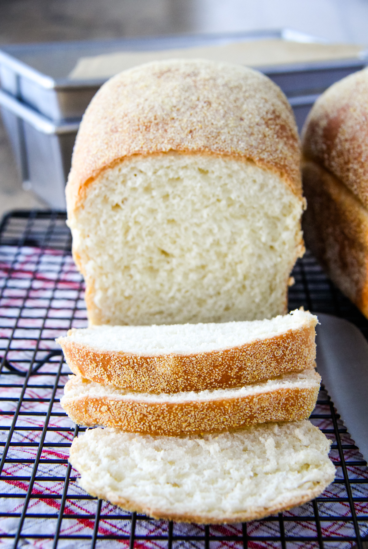 an English Muffin Loaf cut into slices, sits on a wire cooling rack