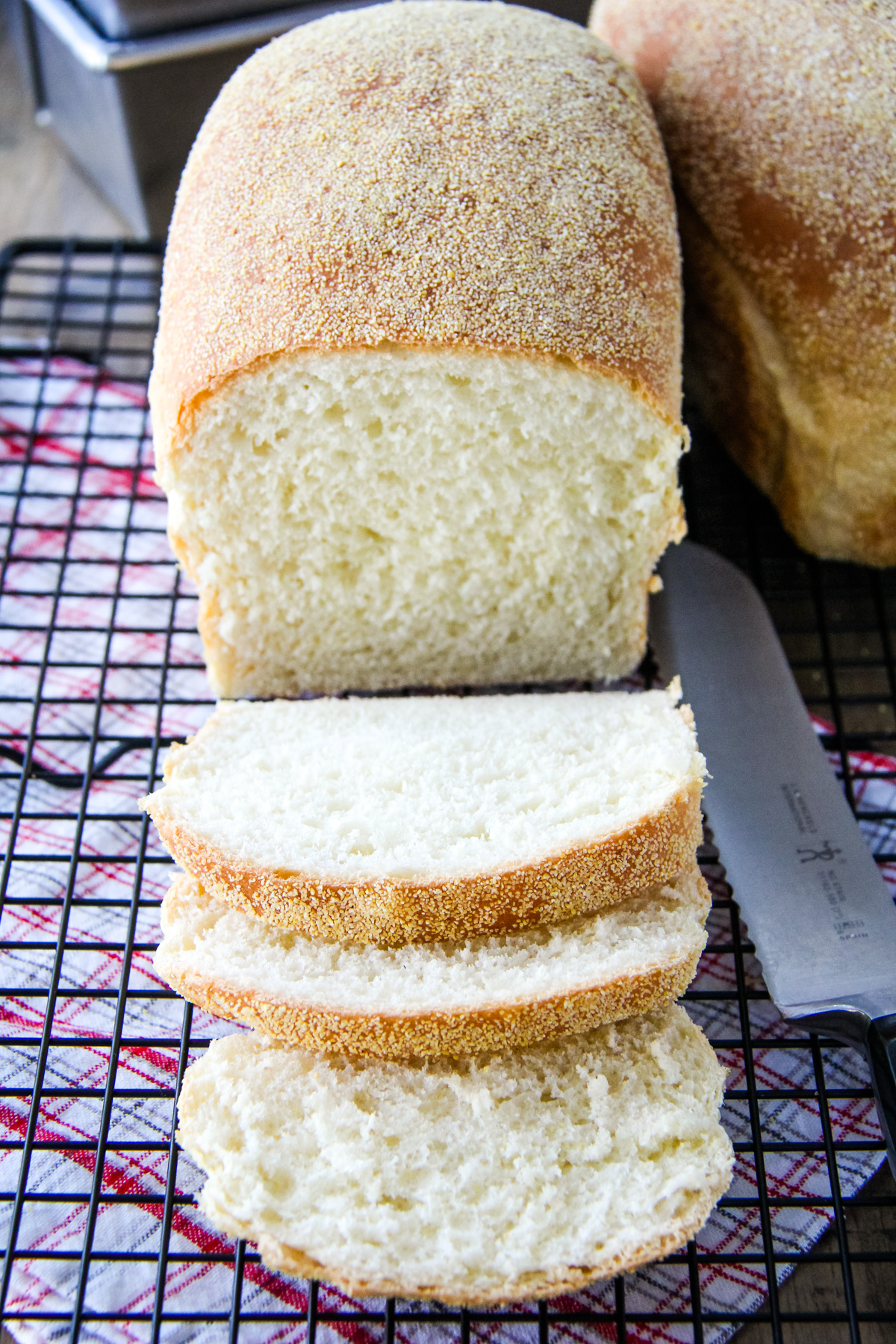 an English Muffin Loaf cut into slices, sits on a wire cooling rack