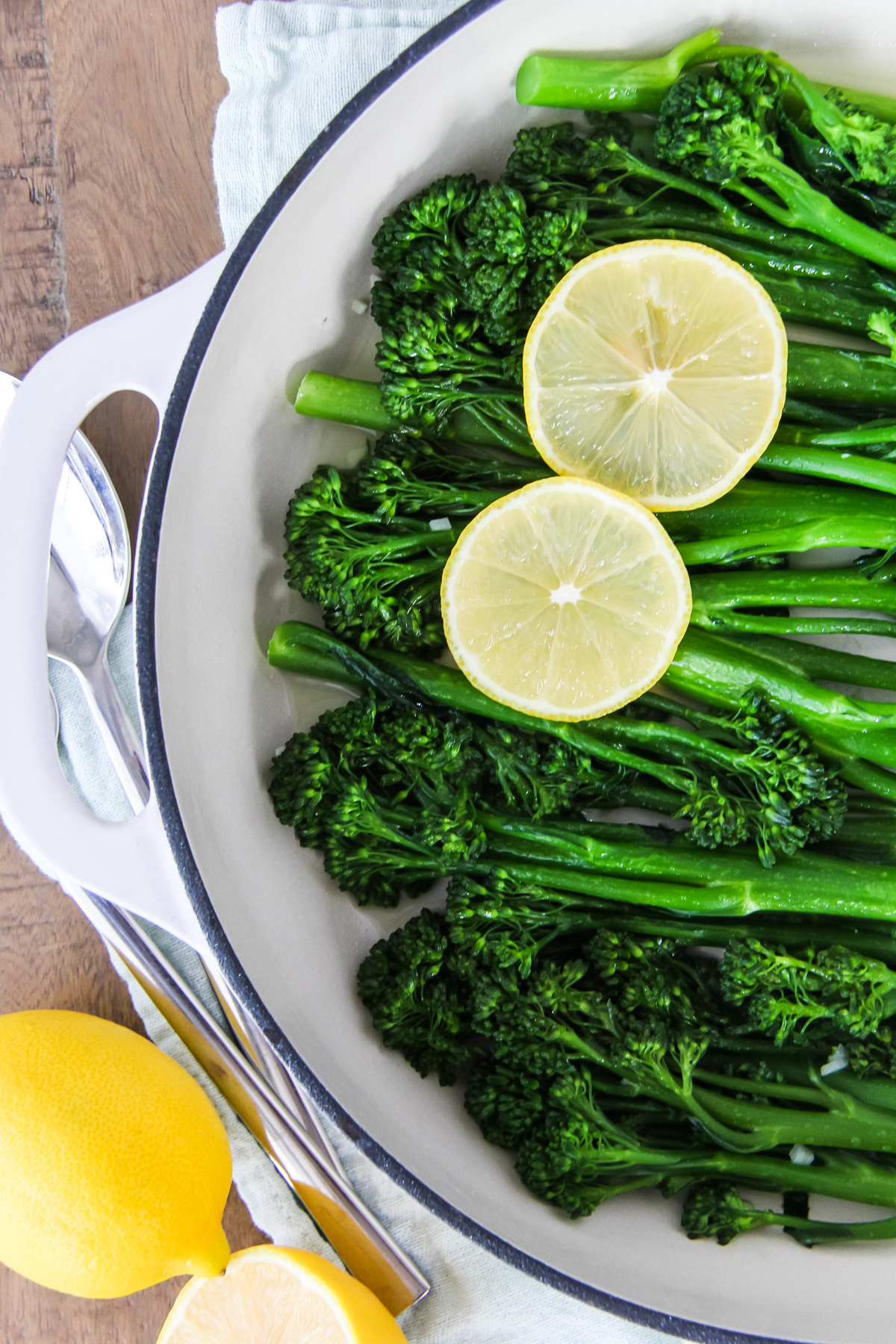 a top down close up of half of a pan of lemon garlic broccolini. two slices of lemon rest on the broccolini.