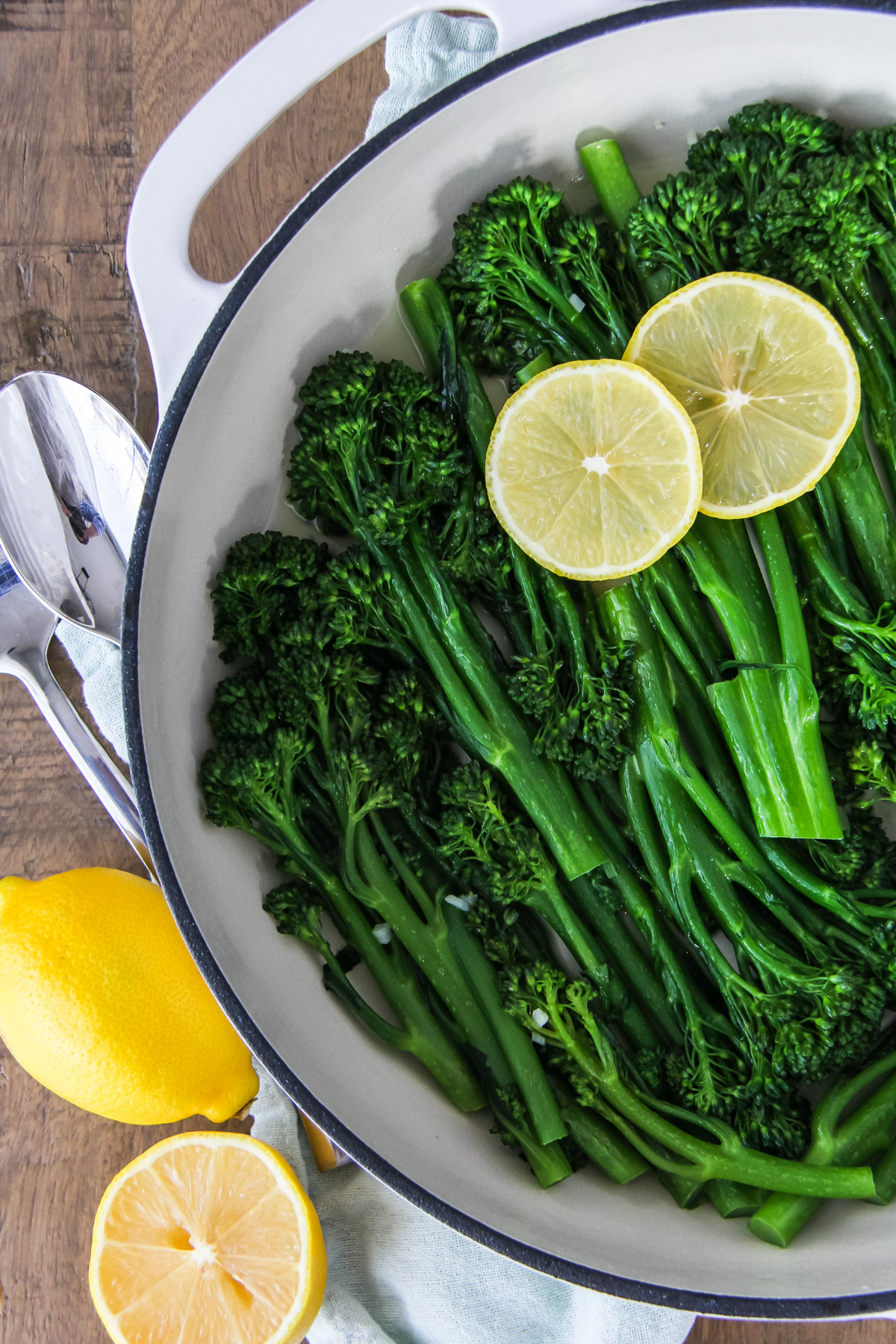 a top down close up of half of a pan of lemon garlic broccolini. two slices of lemon rest on the broccolini.