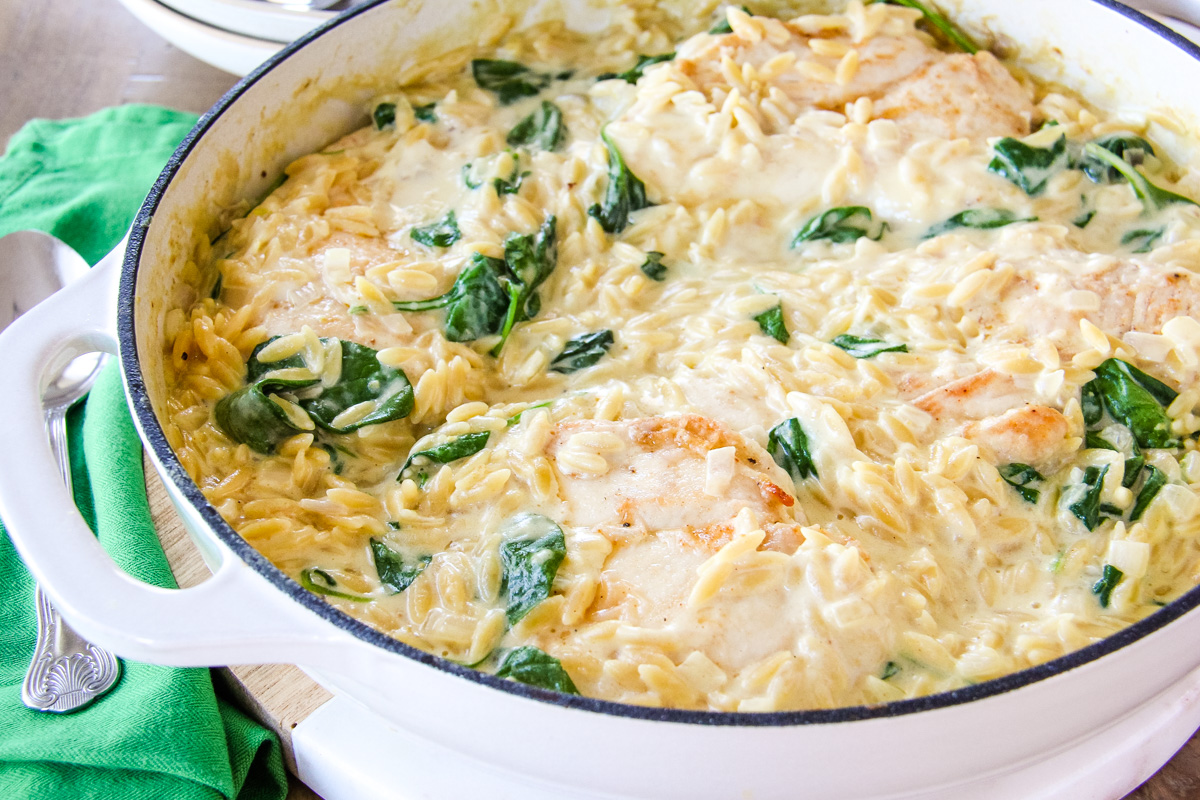 a close up image of a dish of creamy chicken orzo with spinach