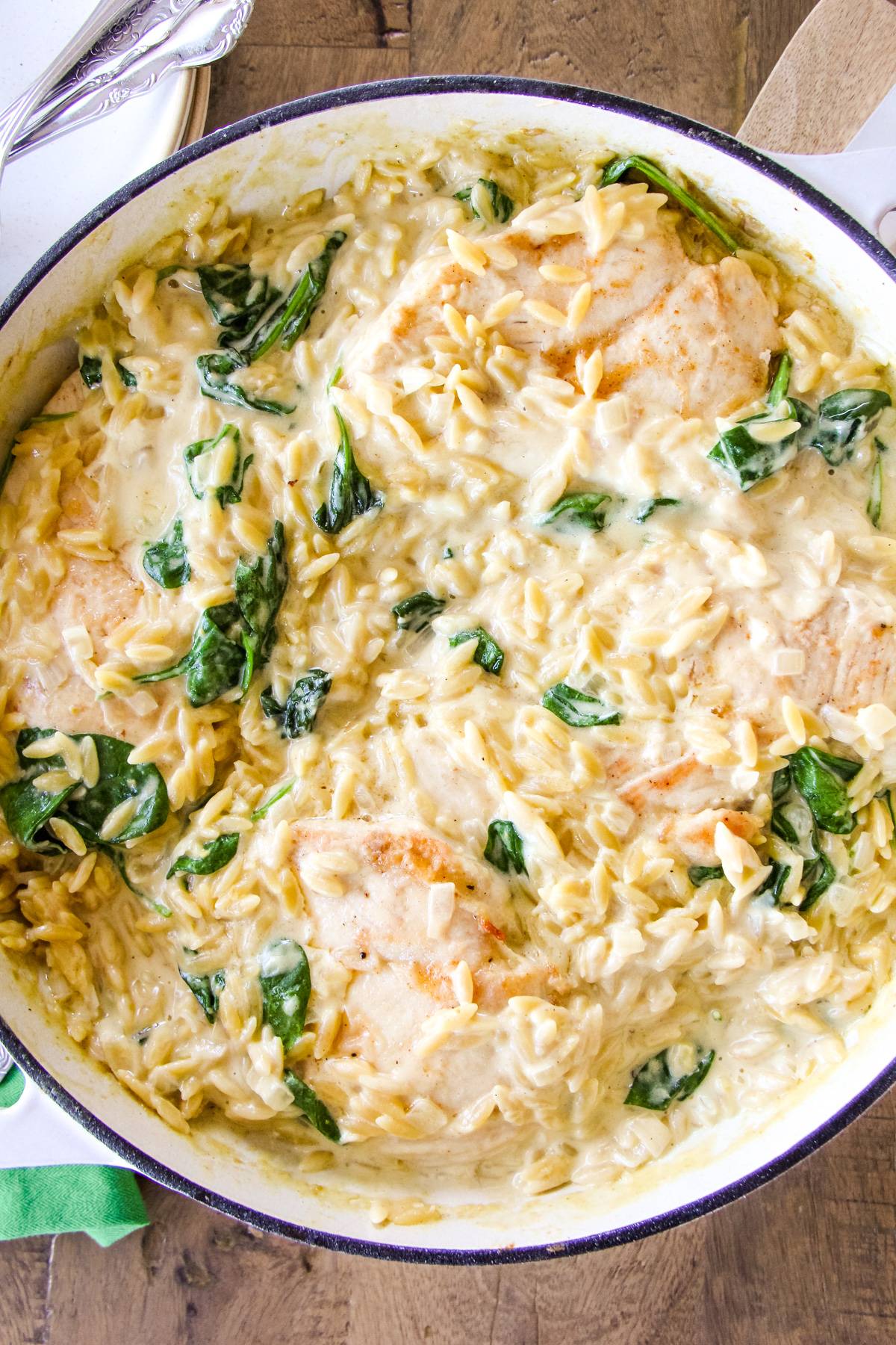 a top down image of a dish of creamy chicken orzo with spinach