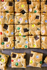 a top down image of chocolate chip cookie bars dotted with coloured candy
