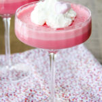 a coupe glass filled with pink jello whip and a dollop of whipped cream