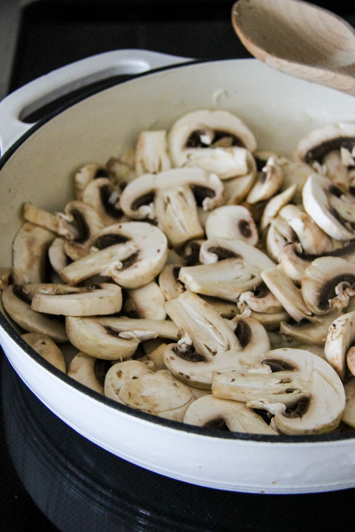 an enamel dish filled with sliced raw mushrooms