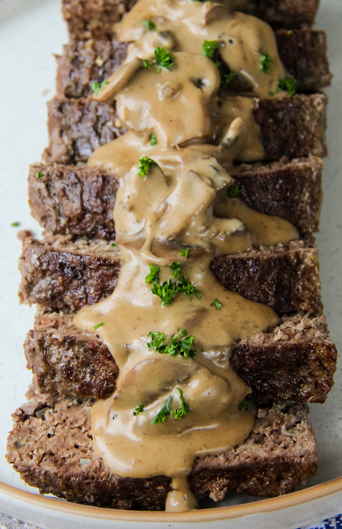 a plate filled with sliced beef stroganoff meatloaf smothered in gravy