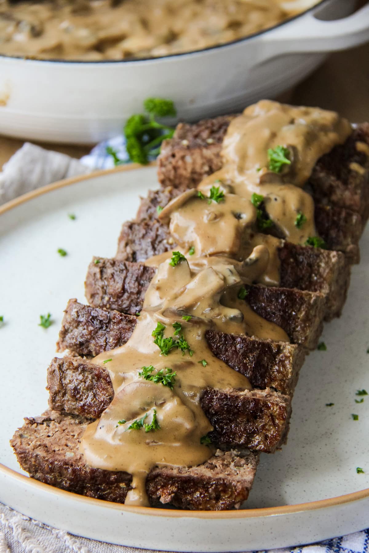 This is a photo of Beef Stroganoff Meatloaf cut into slices on a plate topped with gravy.