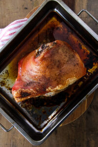a top down image of a cooked Slow Roasted Pork Shoulder Recipe (Picnic Pork Roast) in a metal roasting pan