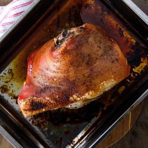 a top down image of a cooked Slow Roasted Pork Shoulder Recipe (Picnic Pork Roast) in a metal roasting pan