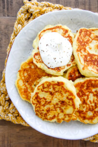 a top down image of a plate of mashed potato pancakes with a dollop of sour cream