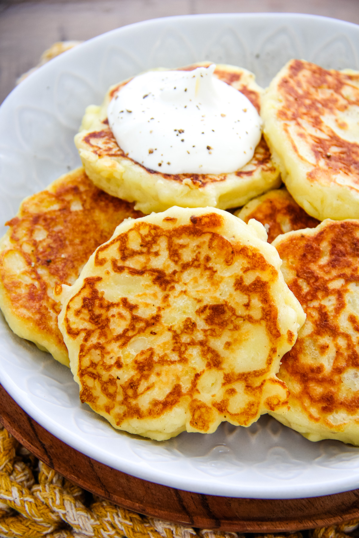 a plate of mashed potato pancakes with a dollop of sour cream