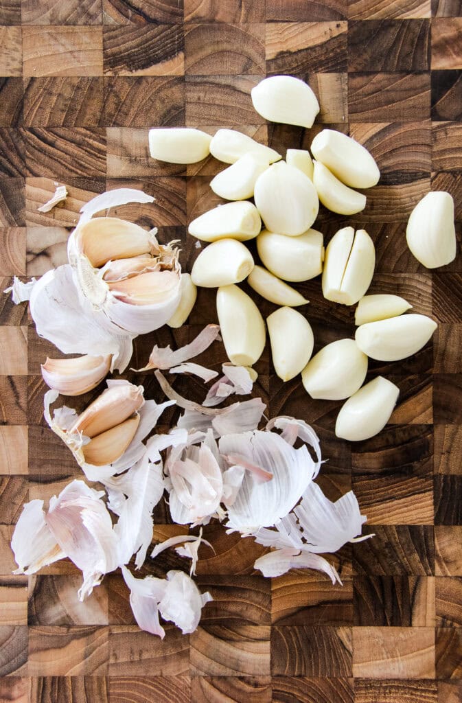 peeled garlic cloves on a wooden cutting board