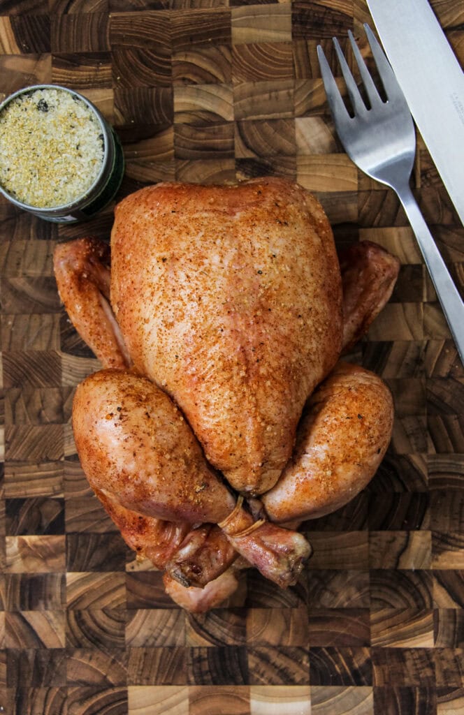 a roast whole chicken on a wooden cutting board