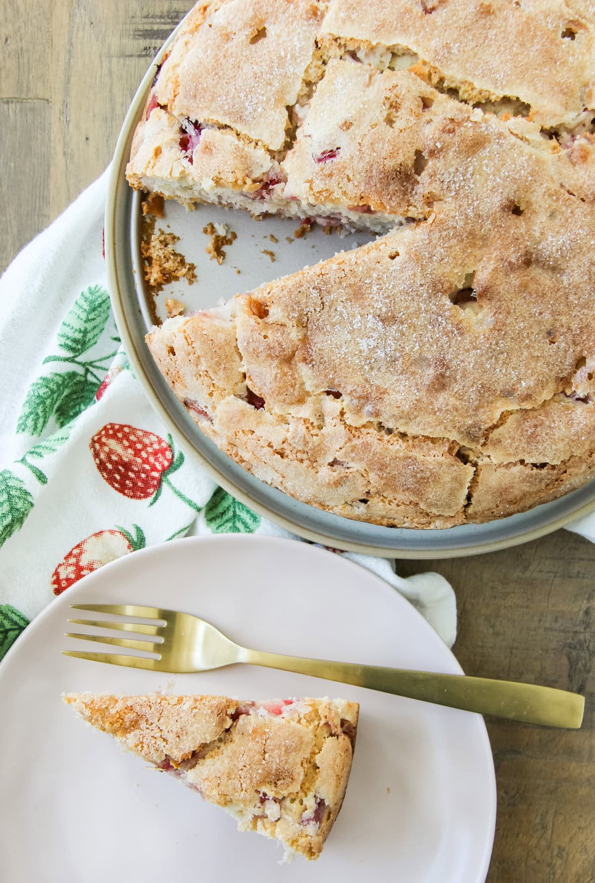 a slice of Strawberry Buttermilk Cake sits on a plate next to the cake